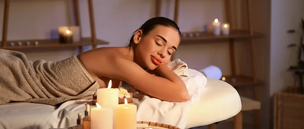 Woman relaxing on a spa massage bed with candles and soft lighting during a wellness visit Copy Alt