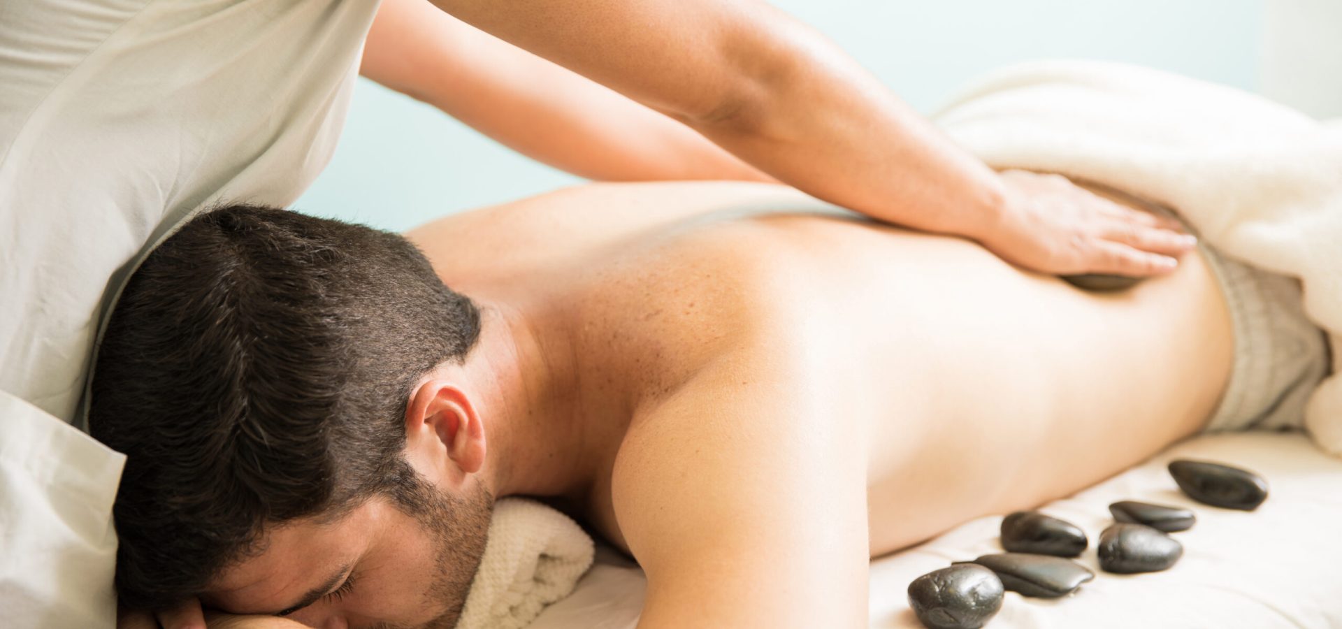 closeup-female-therapist-giving-hot-stone-massage-young-man-spa-scaled.jpg